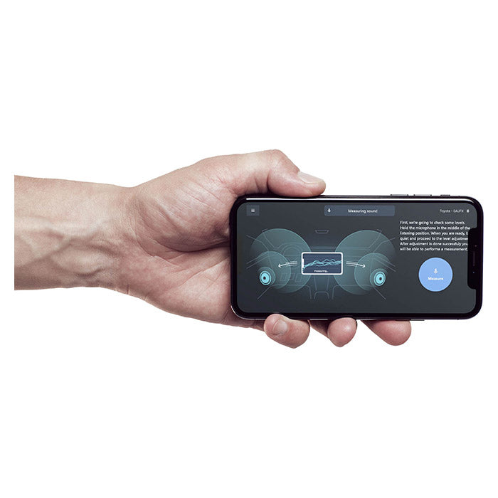 Hånd holder telefon med Alpine OPTIM8 DSP-app til lydmåling i bil