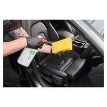 Mand renser bilsæde med Autoglym Interior Cleaner og svamp.