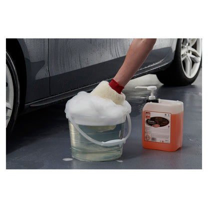 Hånd vasker bil med skumfyldt spand og Autoglym shampoo.
