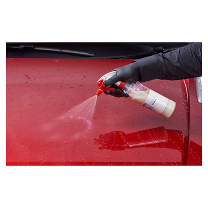 Hånd sprøjter Autoglym Express Wax på en rød bilhjelm for beskyttelse