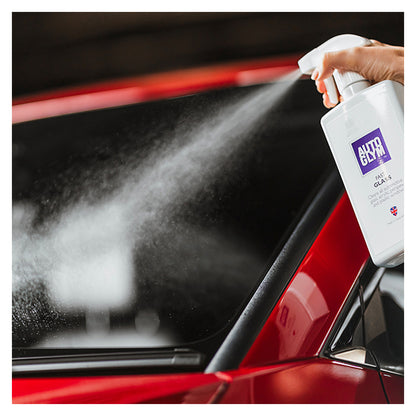 Person sprøjter Autoglym Fast Glass ruderens på en rød bilrude.