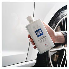 Autoglym Intensive Tar Remover flaske holdes mod hvid bil og hjul