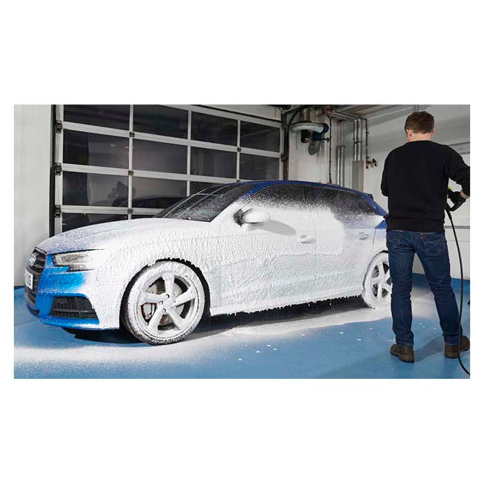 Mand påfører Autoglym Polar Blast skumforvask på en blå bil i garage.