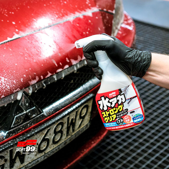 Soft99 Stain Cleaner Strong Type sprøjtes på en rød bilfront.