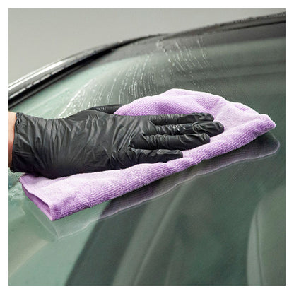 Hånd med sort handske tørrer bilrude med lilla mikrofiberklud